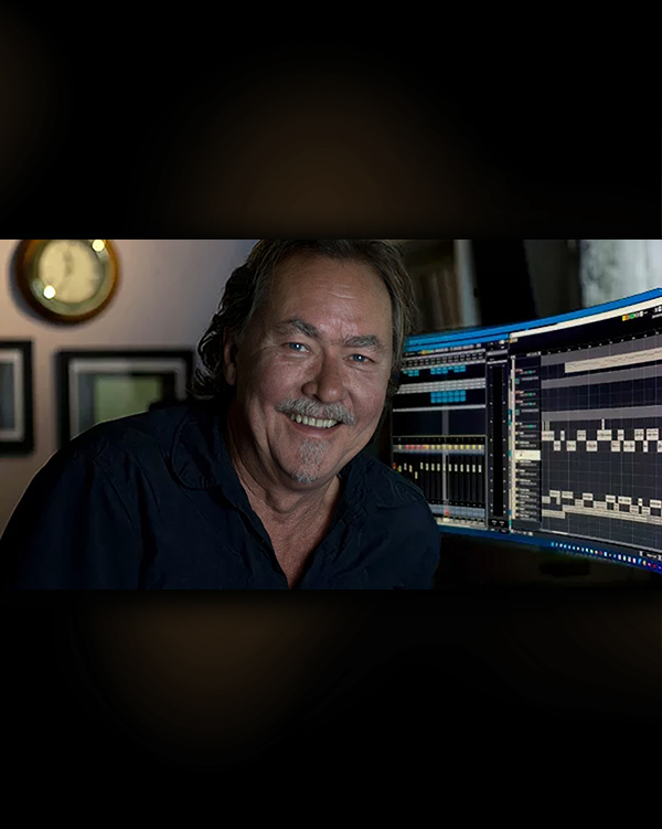 Jeff Watkinson at the desk in the YES AUDIO control room, smiling, multitrack session on the monitors behind him
